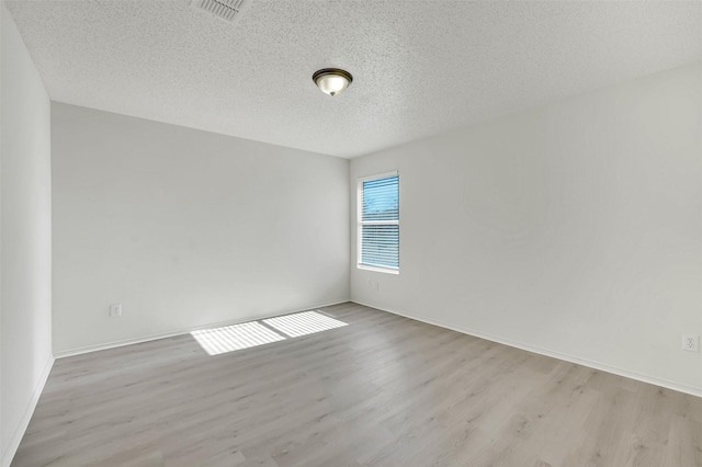 empty room featuring light hardwood / wood-style flooring and a textured ceiling