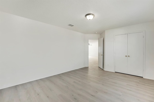 unfurnished bedroom featuring a closet, light hardwood / wood-style flooring, and a textured ceiling