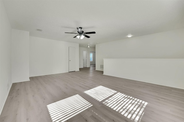 additional living space with ceiling fan, a textured ceiling, and light wood-type flooring