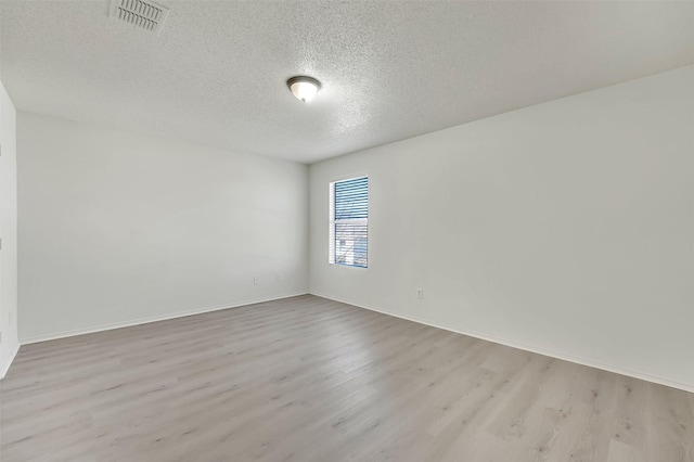 empty room featuring a textured ceiling and light hardwood / wood-style flooring