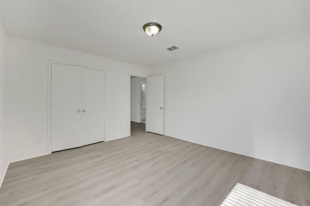 unfurnished bedroom featuring a closet and light wood-type flooring