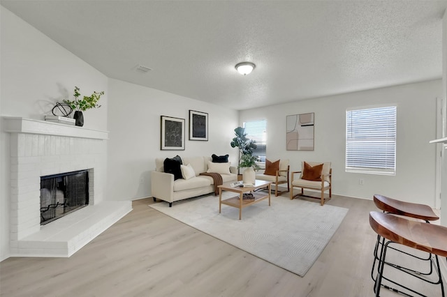 living room with a fireplace, light hardwood / wood-style flooring, and a textured ceiling