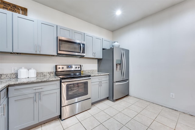 kitchen featuring stainless steel appliances, gray cabinets, and light stone counters