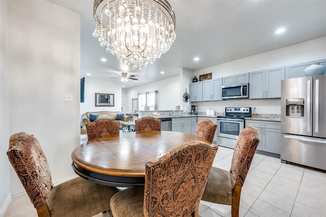 tiled dining area featuring ceiling fan with notable chandelier and sink