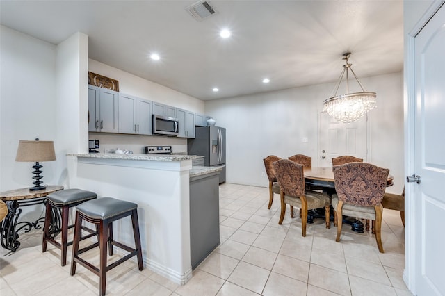 kitchen featuring pendant lighting, appliances with stainless steel finishes, kitchen peninsula, and light stone countertops