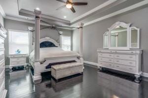 bedroom with dark wood-type flooring, ornamental molding, and a raised ceiling