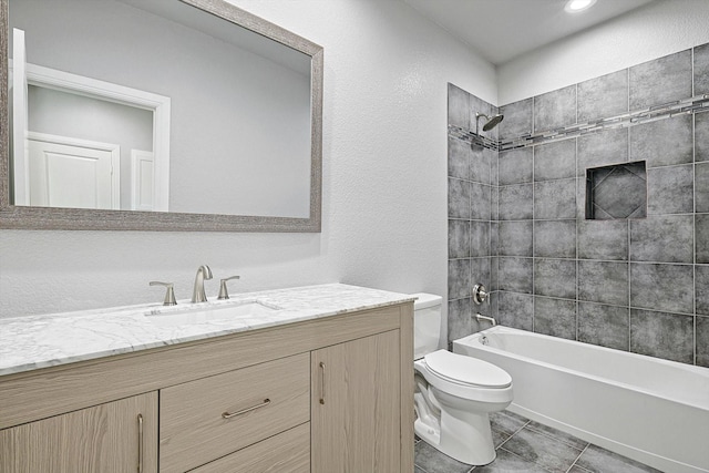 full bathroom featuring tiled shower / bath combo, vanity, tile patterned flooring, and toilet