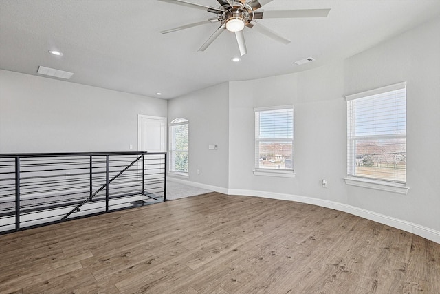 empty room featuring ceiling fan, a healthy amount of sunlight, and light hardwood / wood-style flooring