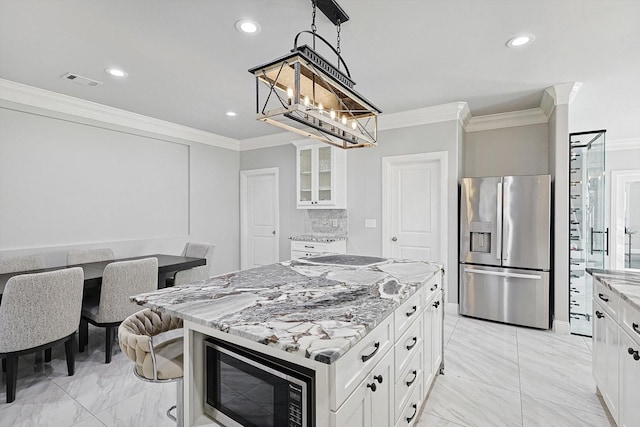 kitchen with a kitchen island, white cabinets, hanging light fixtures, stainless steel refrigerator with ice dispenser, and light stone countertops