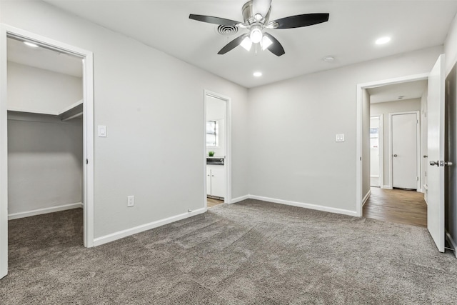 unfurnished bedroom featuring ceiling fan, a walk in closet, a closet, and carpet