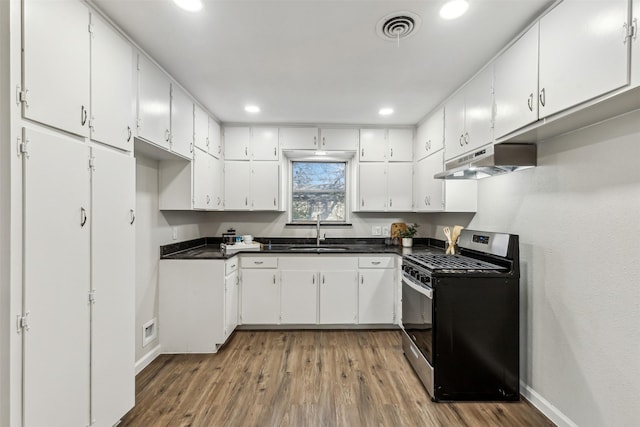 kitchen with hardwood / wood-style floors, sink, stainless steel range with gas stovetop, and white cabinets