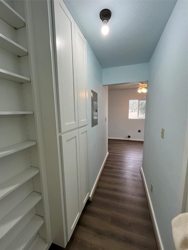 corridor featuring electric panel, baseboards, built in features, dark wood-style floors, and a textured ceiling