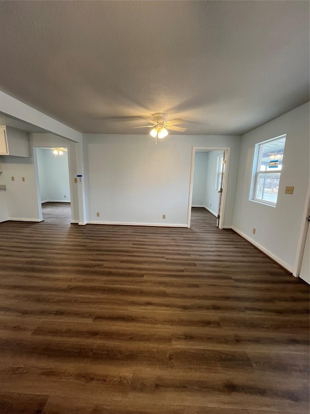 unfurnished living room featuring dark wood-style floors, a textured ceiling, baseboards, and a ceiling fan