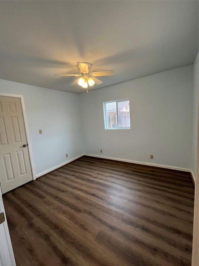 spare room featuring dark wood-type flooring, baseboards, and a ceiling fan