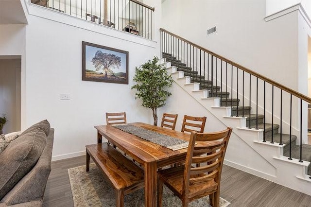 dining room with a towering ceiling and dark hardwood / wood-style flooring