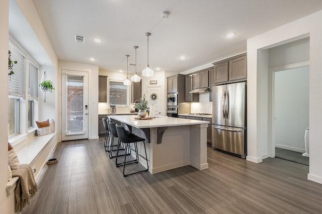 kitchen with decorative light fixtures, stainless steel appliances, a center island, and a breakfast bar