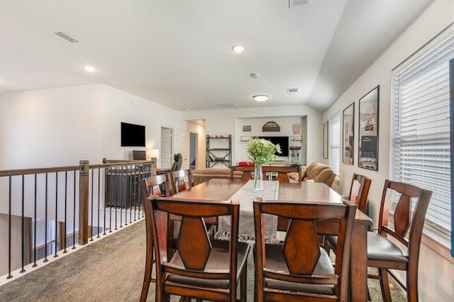 carpeted dining space featuring lofted ceiling and a wealth of natural light