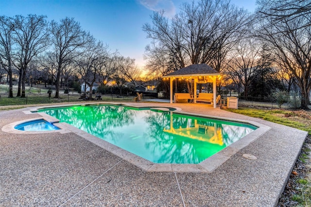 pool at dusk featuring a gazebo, an in ground hot tub, an outdoor hangout area, and a patio area