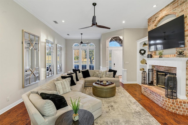 living room with crown molding, ceiling fan, wood-type flooring, and a fireplace