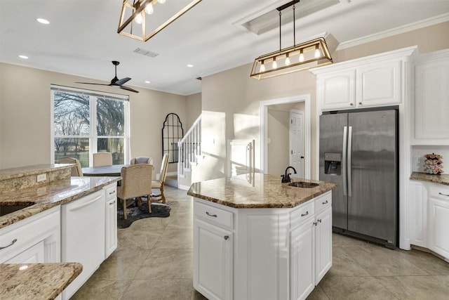 kitchen featuring sink, hanging light fixtures, stainless steel refrigerator with ice dispenser, light stone counters, and a center island with sink