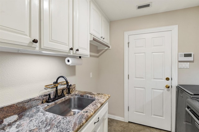 kitchen with white cabinetry, sink, light tile patterned floors, and dark stone counters