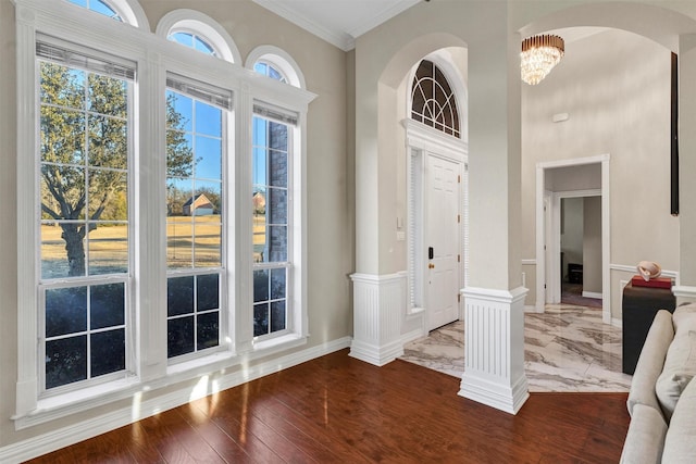 foyer featuring hardwood / wood-style flooring, ornamental molding, and a chandelier