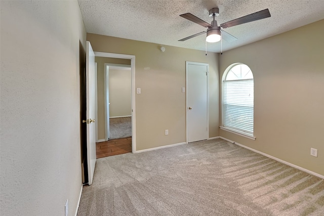 unfurnished bedroom with a closet, ceiling fan, light colored carpet, and a textured ceiling