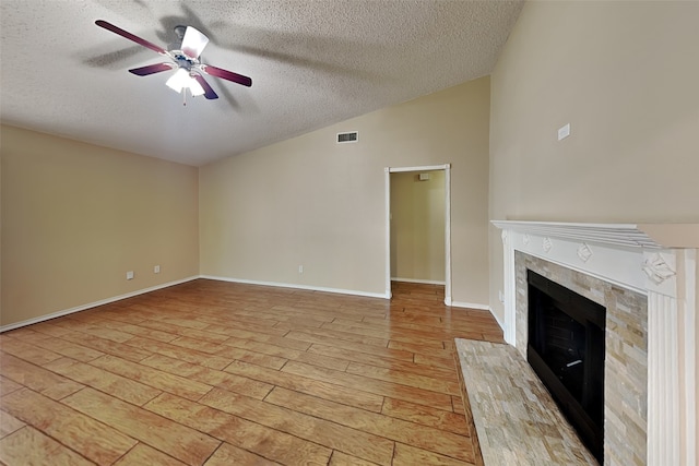 unfurnished living room with lofted ceiling, a textured ceiling, light wood-type flooring, ceiling fan, and a high end fireplace