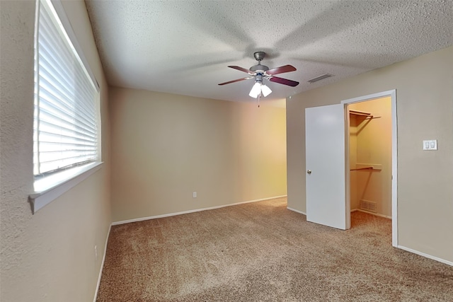 unfurnished bedroom featuring ceiling fan, a walk in closet, light colored carpet, and a closet