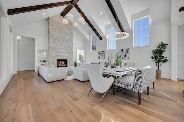 dining area featuring beamed ceiling, a fireplace, light hardwood / wood-style floors, and high vaulted ceiling