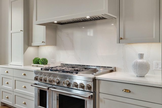 kitchen featuring tasteful backsplash, double oven range, premium range hood, and gray cabinets