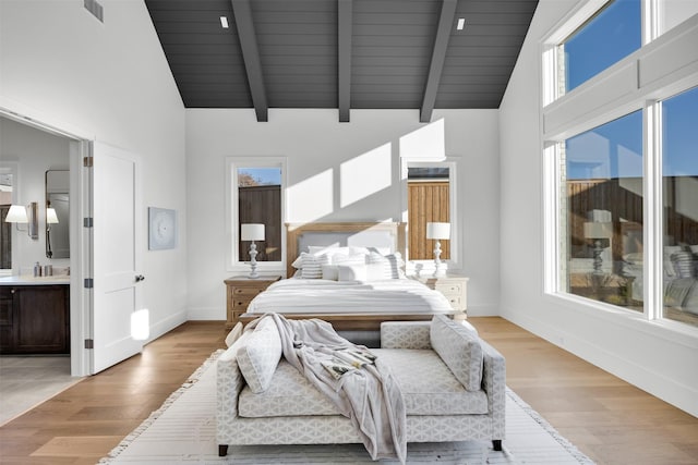 bedroom with multiple windows, connected bathroom, and light hardwood / wood-style flooring