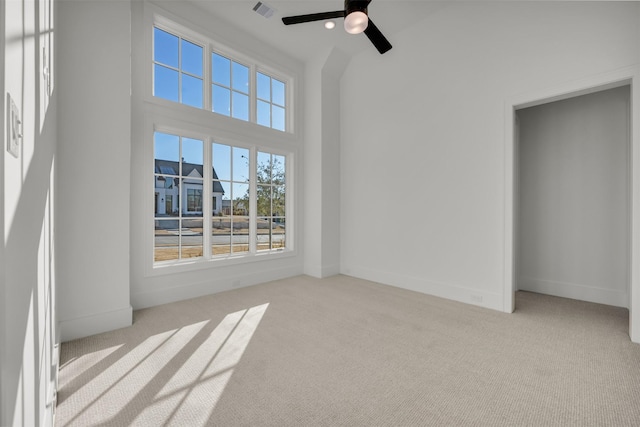 interior space featuring light carpet, a towering ceiling, and ceiling fan