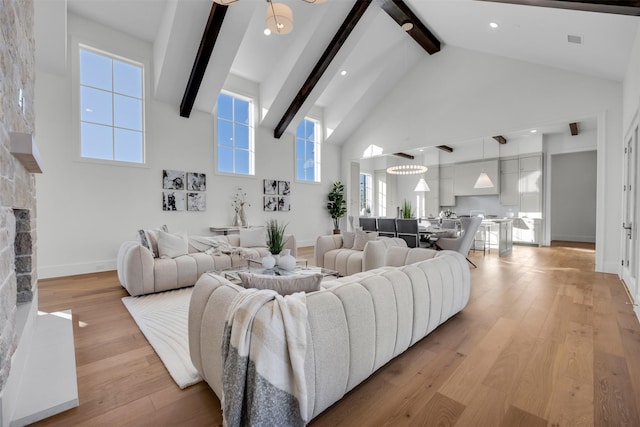 living room with beamed ceiling, a stone fireplace, high vaulted ceiling, and light hardwood / wood-style floors