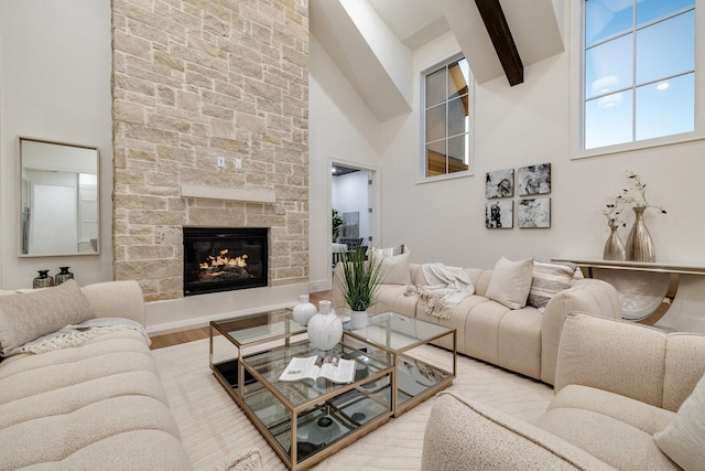 living room featuring beamed ceiling, wood-type flooring, a stone fireplace, and high vaulted ceiling