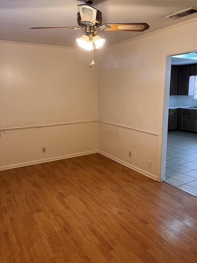 spare room featuring crown molding, wood-type flooring, and ceiling fan