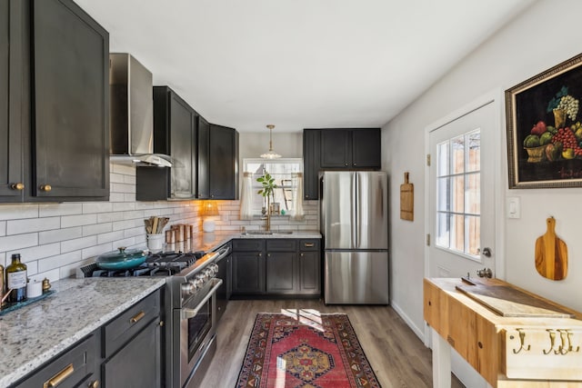 kitchen featuring wall chimney exhaust hood, appliances with stainless steel finishes, plenty of natural light, and decorative backsplash