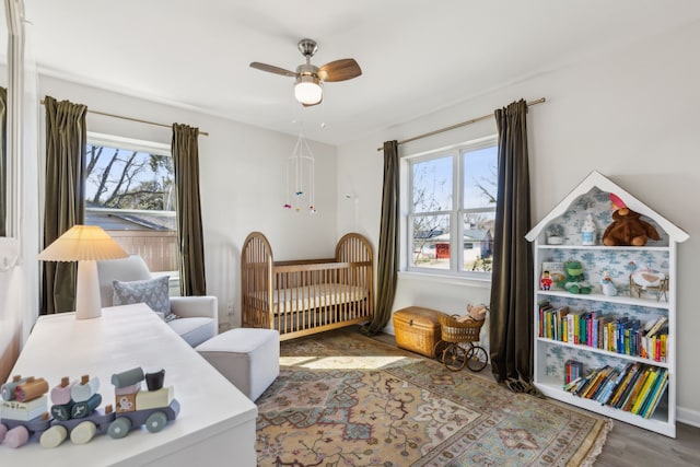 bedroom featuring hardwood / wood-style flooring, ceiling fan, and a crib