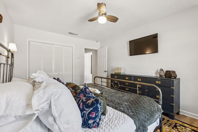 bedroom with baseboards, visible vents, a ceiling fan, wood finished floors, and a closet