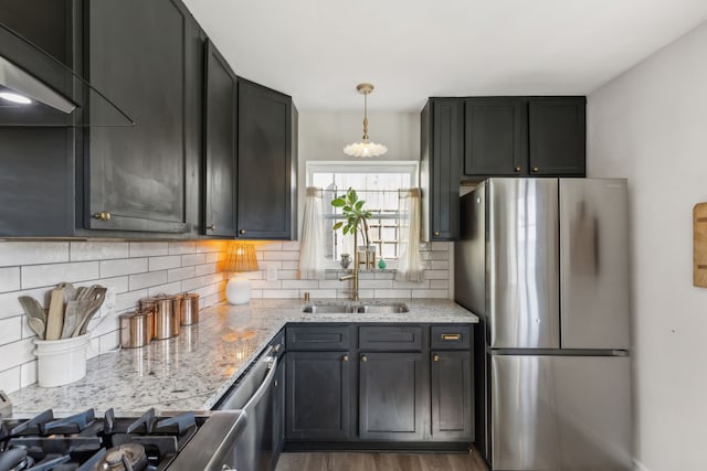 kitchen with sink, hanging light fixtures, light stone counters, stainless steel appliances, and dark wood-type flooring