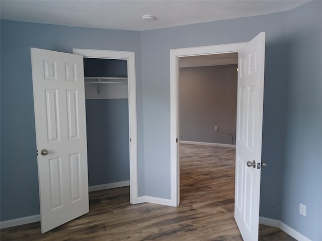 unfurnished bedroom featuring dark hardwood / wood-style flooring and a closet