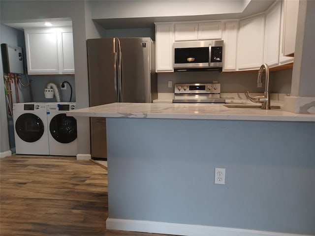 kitchen with appliances with stainless steel finishes, water heater, white cabinetry, sink, and washing machine and clothes dryer