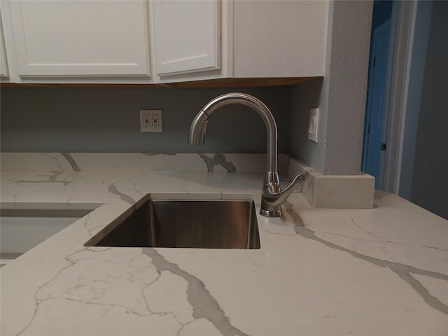 kitchen featuring white cabinetry, sink, and light stone counters