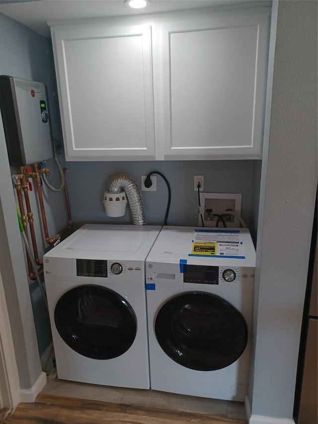 laundry area with cabinets, washer and clothes dryer, hardwood / wood-style floors, and water heater