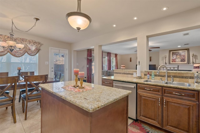 kitchen featuring sink, dishwasher, hanging light fixtures, light stone counters, and a kitchen island