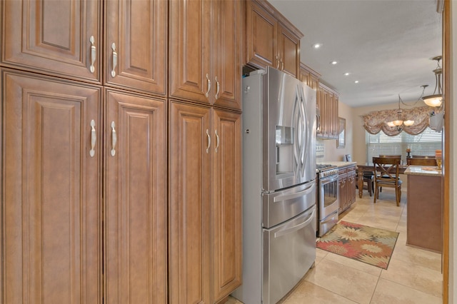 kitchen featuring pendant lighting, light tile patterned floors, stainless steel appliances, light stone countertops, and a chandelier