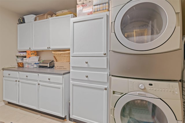 washroom featuring cabinets, stacked washer / drying machine, and light tile patterned floors