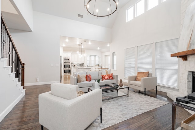 1108 Canterbury Ln, Forney, TX 75126 - living area featuring a chandelier, a towering ceiling, dark wood-style flooring, a stone fireplace, and stairs