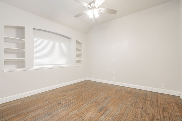 empty room featuring wood-type flooring, lofted ceiling, built in features, and ceiling fan