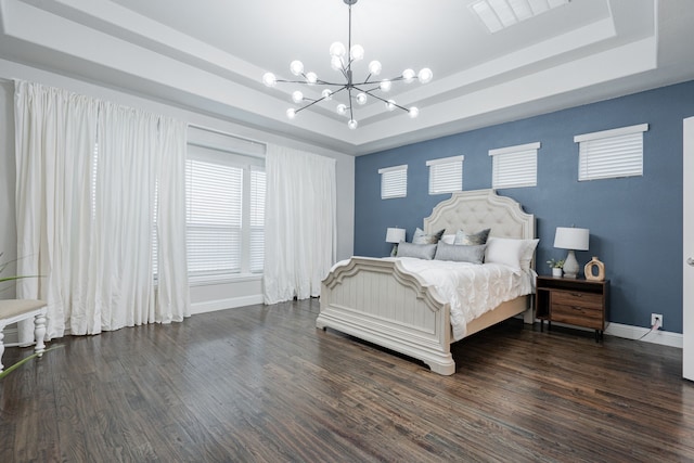 bedroom featuring a raised ceiling, dark hardwood / wood-style floors, and a chandelier